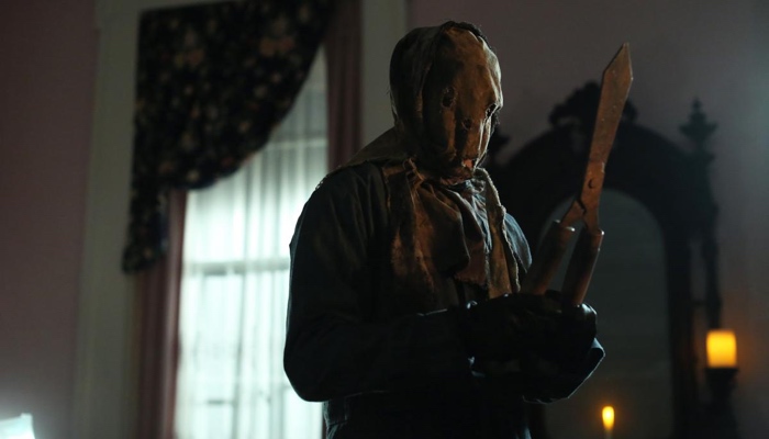 The Killer wearing an Anna Hobbs mask and holds garden shears in Scream season 2 Halloween Special